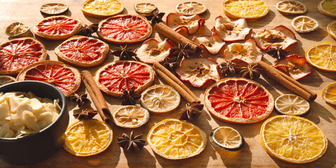 Various dried fruits and spices for winter and the Christmas season. Sliced ​​dried citrus fruits, apple rings with cinnamon sticks and star anise on wood. Preparations for christmas celebrations.