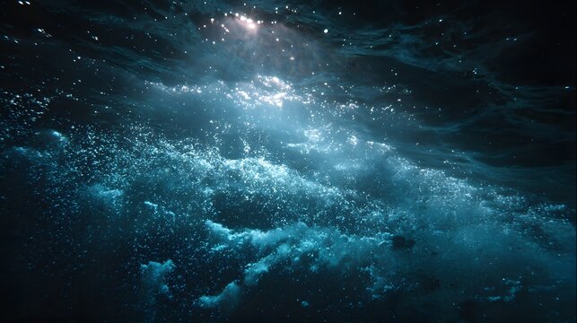 Deep ocean water shows light rays penetrating the dark surface with numerous bubbles rising