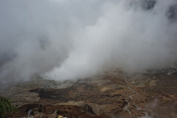 Fototapeta premium Aerial view showing a geothermal landscape with volcanic fumes rising through the clouds, showcasing the raw power and beauty of nature with earthy color tones