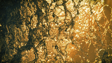 A blurred natural background of drops and streams of falling water at sunset.