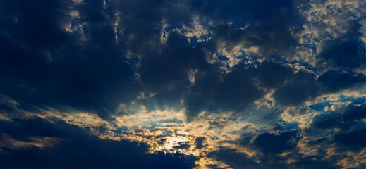 Dark cumulus clouds and sunbeams at sunset.