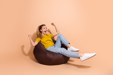 Cheerful young woman enjoying leisure time on bean bag with joyful expression and stylish outfit