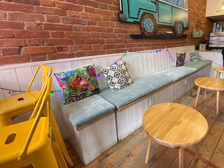 Cozy cafe corner with colorful pillows and wooden furniture. Relaxed social atmosphere, urban comfort, and creative interior design with eclectic details.