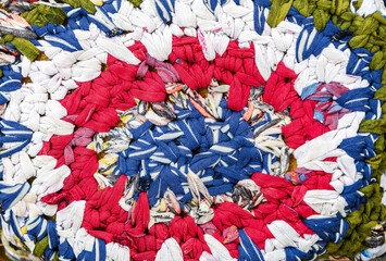 Vintage homespun doormat made from strips of cloth as background. Texture of a homemade rug from different fabrics. Round knit mat