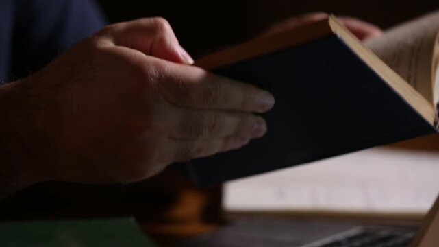 Close-up of hands comparing an old book and typing rapidly on a modern laptop. Blending history, research, and digital workflow.
