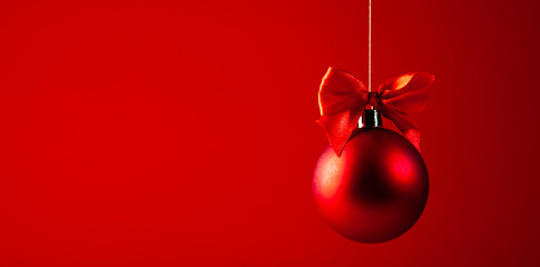 Red christmas ball with red bow on red background.