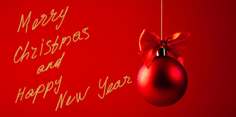 Red christmas ball with red bow on red background with text Merry Christmas and Happy New Year