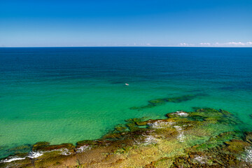 Turquoise sea and rocky coast with clear shallow water and blue horizon under bright summer sky, captured near Byala on the Black Sea coast of Bulgaria