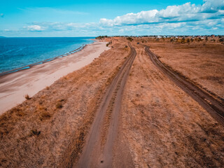 Coastal Road's Embrace: An aerial view captures a scenic coastal road winding its way through golden fields and meeting the serene ocean, offering a journey of exploration and tranquility. 