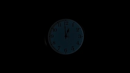 Classic wall clock showing midnight in a dark room