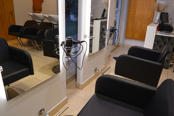 A modern hair salon interior with black chairs, large mirrors, and minimalist decor. Concept for a beauty salon professional's workspace, modern customer service