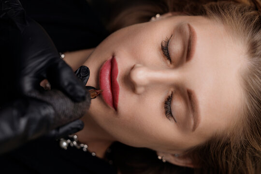 Top view Caucasian female undergoing lip tattoo permanent procedure with precision
