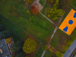 An eye-level view, capturing the intricate grid of the urban landscape, from the architectural patterns of buildings to the green spaces of parks and the colorful basketball court.