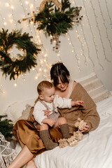 At Christmas, a mother and son play with a wooden train on the bed.