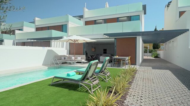 Luxurious villa showcasing a private swimming pool, sun loungers, patio furniture, and an open plan living area, creating a perfect setting for relaxation and entertainment