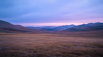 Obraz premium A picturesque landscape featuring a broad plain and far - off mountain ranges bathed in a soft pastel - colored sky.