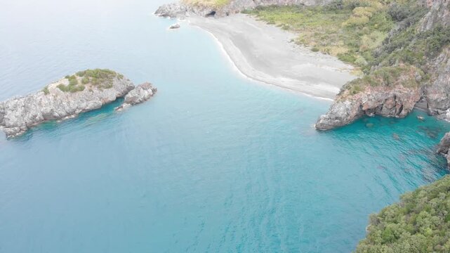 Aerial view of Arcomagno coast in Calabria Italy showing turquoise sea meeting rugged cliffs and hidden caves surrounded by lush Mediterranean vegetation symbolizing untouched natural beauty