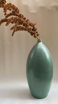 ikebana of dried floral in large green ceramic vessel