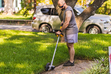 Man is using a weed eater on grass