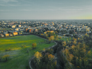 Cityscape and Serene Green Spaces: An expansive cityscape stretches towards the horizon, complemented by verdant meadows and tranquil trees in the foreground.