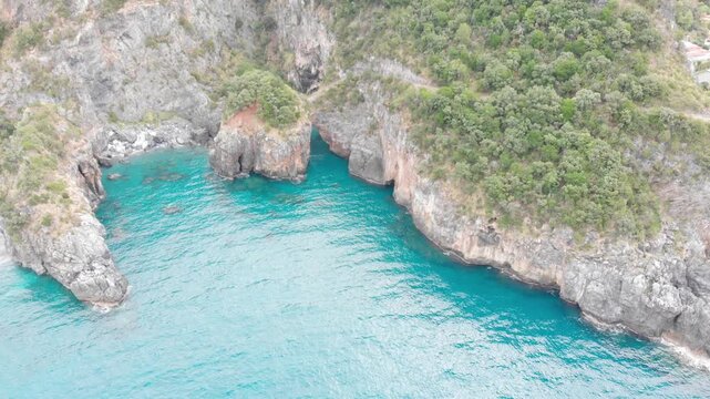 Aerial view of Arcomagno coast in Calabria Italy showing turquoise sea meeting rugged cliffs and hidden caves surrounded by lush Mediterranean vegetation symbolizing untouched natural beauty