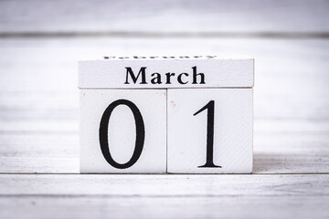 March 01 indicates the arrival of a new month and signifies the transition into spring. Wooden calendar blocks display February and March on a textured background.