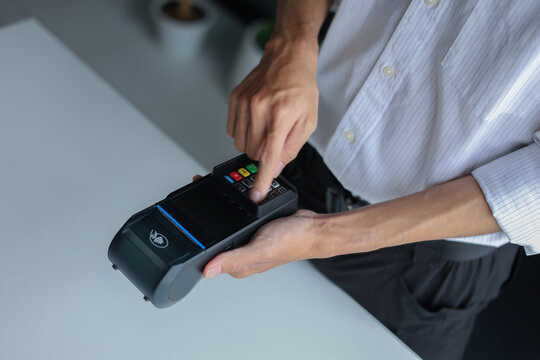 A person using a point-of-sale (POS) terminal, also known as a credit card machine, to process a transaction.