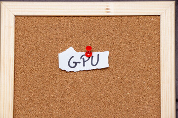 Handwritten note saying GPU pinned to corkboard with a red pushpin. Ideal for topics related to technology, computing, or graphics. Emphasizes organization and reminders.