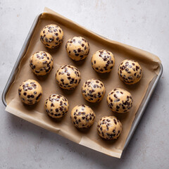 Raw cookie dough balls with chocolate chips on baking tray