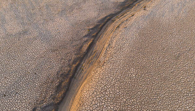 Arid cracked earth with path leading into distance - Powered by Adobe