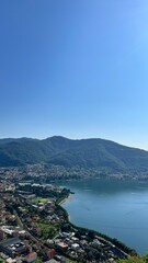 Panoramic Serenity: Breathtaking vista unfolds, showcasing a serene lake and a charming town nestled beside it, all under a clear sky.