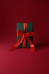 New Year's and Christmas themed images, mockup postcard, green gift box with red bow on a red background , gift wrapping