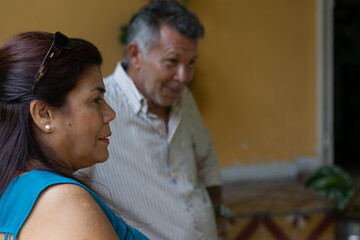 Mature hispanic couple sharing a relaxed, candid conversation outdoorssmiling, listening and enjoying casual weekend companionship