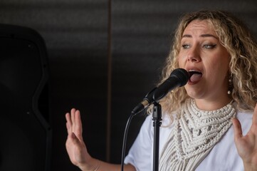 Caucasian woman singing into microphone in music studio. 