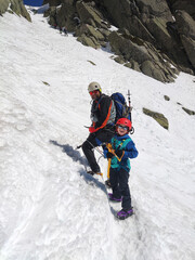 Portrait of a father with his son as they climb a snowy mountain.