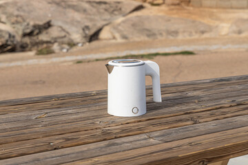 White electric kettle on the gray wooden table background