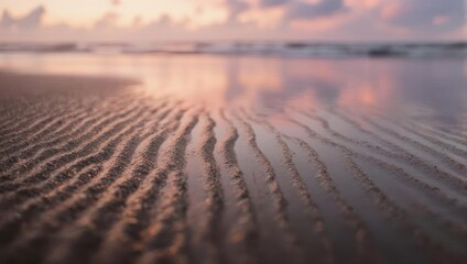 Soft morning light reflects on wet sand, rippled by the tide, with a hazy ocean backdrop