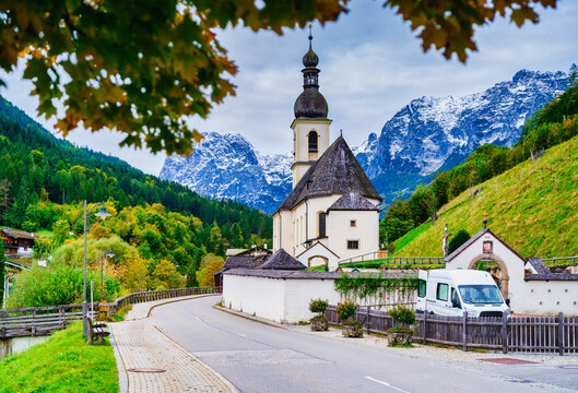 St. Sebastian Church and street framed by tree leaves, Ramsau bei Berchtesgaden, Germany