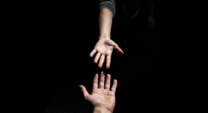 Hands reaching out in dark for help, representing support, connection, partnership, and rescue. - Powered by Adobe