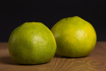 Two Green Pomelo Citrus Fruits on Wooden Table