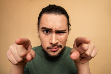 Pointing at the camera with a playful confident expression by a young arabian man in casual green t shirt for lifestyle advertising and fashion stock photo