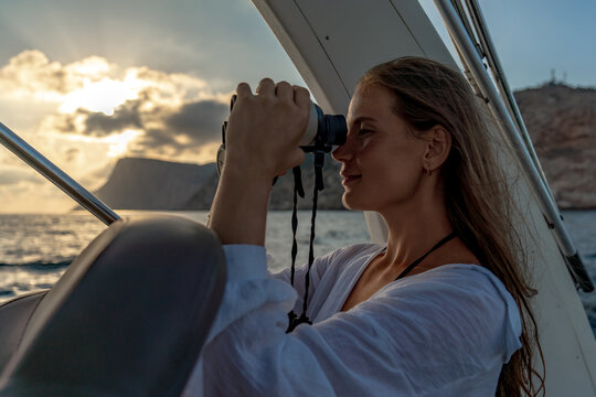 Woman, binoculars, sea, young woman observing through binoculars on yacht at sunset