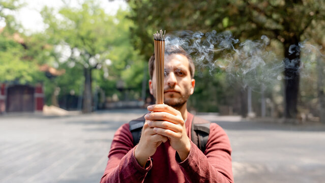 Man holding incense sticks near Lama Temple in Beijing