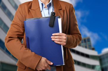 Businesswoman with hidden spy camera near building outdoors, closeup