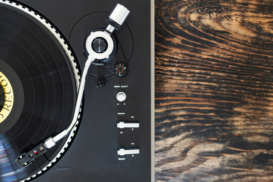 Close-up of a vinyl turntable tonearm on a spinning black record.