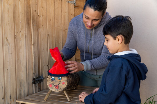 Mother and child decorating a log with a red hat during Tio de Nadal