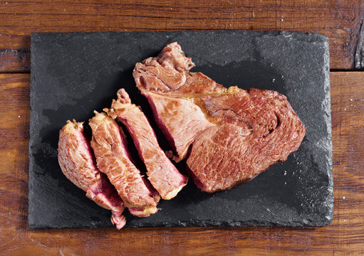 Top view of sliced horse fillet on black slate board