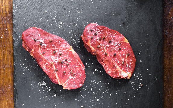 Horse meat fillets with seasoning on slate board