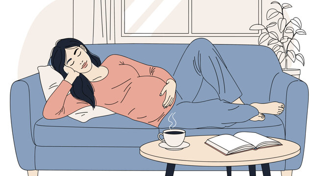 Young asian pregnant female relaxing on a blue sofa, holding her belly, with a book and steaming cup of coffee on a table nearby.