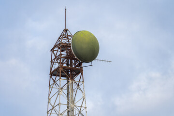 Satellite tower with a large green dish under blue sky